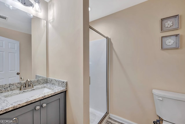 bathroom with vanity, toilet, and a shower with door