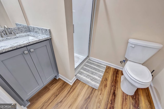 bathroom featuring vanity, toilet, a shower with door, and hardwood / wood-style flooring