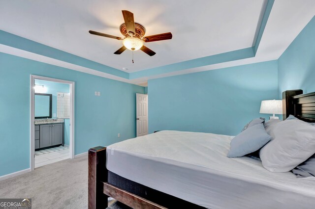 carpeted bedroom featuring connected bathroom, a tray ceiling, and ceiling fan