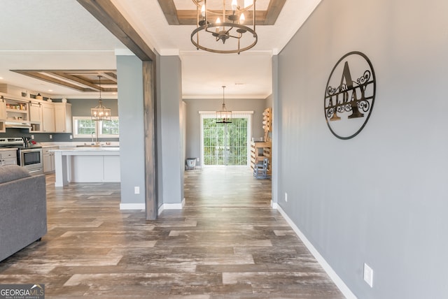 hall with dark hardwood / wood-style flooring, a chandelier, beamed ceiling, sink, and crown molding