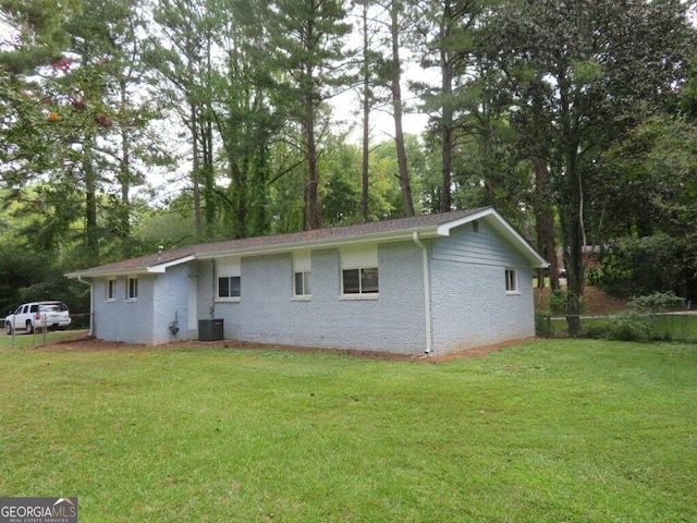 rear view of house featuring a lawn and central AC