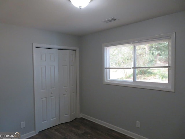 unfurnished bedroom featuring dark hardwood / wood-style floors and a closet