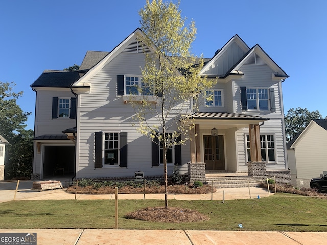 view of front of home featuring covered porch, a garage, and a front lawn