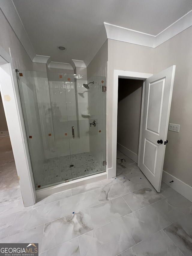 bathroom featuring a shower with shower door and crown molding