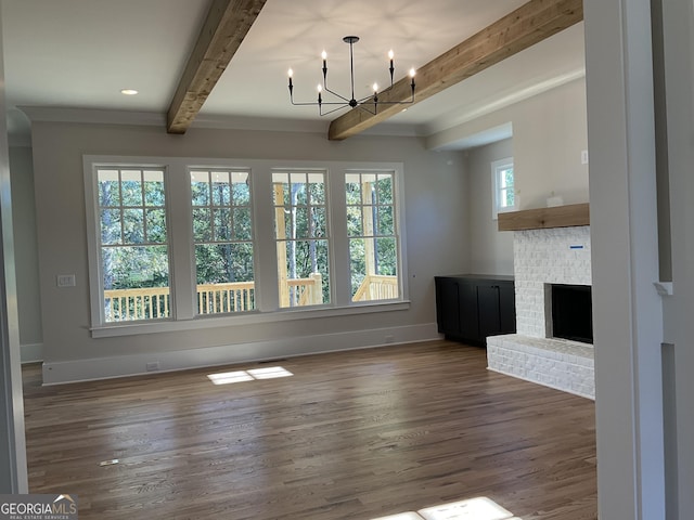 unfurnished living room with beam ceiling, a chandelier, a healthy amount of sunlight, and a brick fireplace