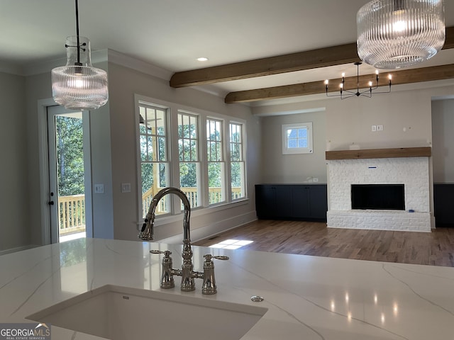 kitchen with sink, pendant lighting, beamed ceiling, a notable chandelier, and a fireplace