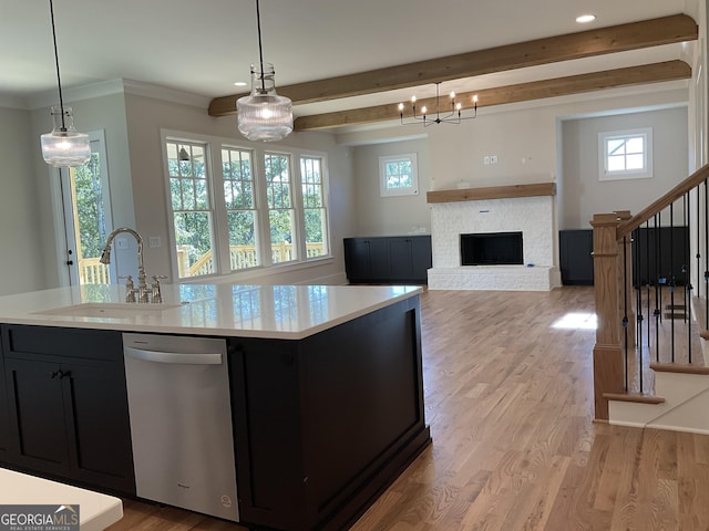 kitchen featuring light wood-type flooring, a brick fireplace, sink, pendant lighting, and dishwasher