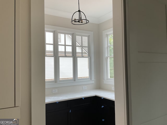 interior space with light stone counters, ornamental molding, hanging light fixtures, and an inviting chandelier