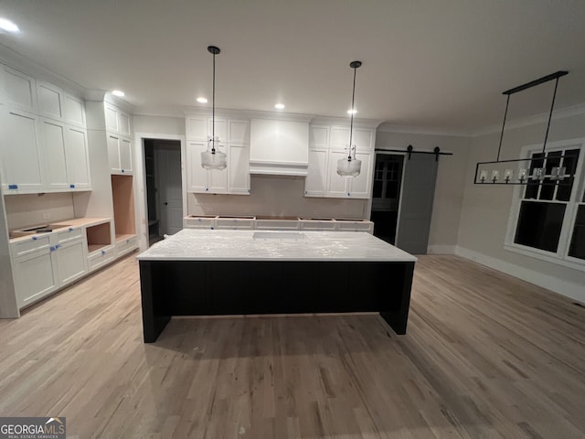 kitchen with a barn door, white cabinetry, a kitchen island, and pendant lighting