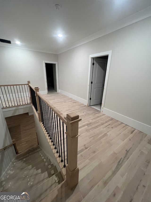 stairs with hardwood / wood-style floors and ornamental molding