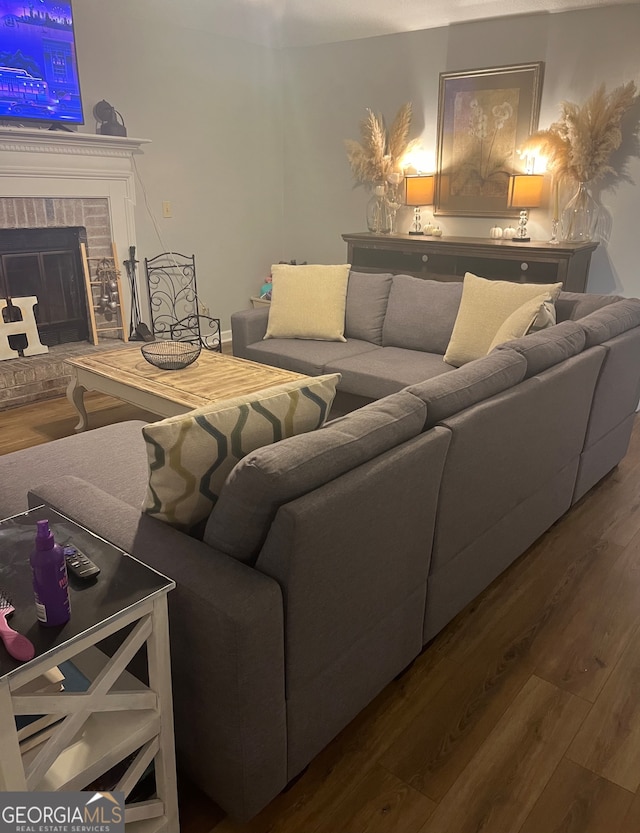 living room with a brick fireplace and hardwood / wood-style floors