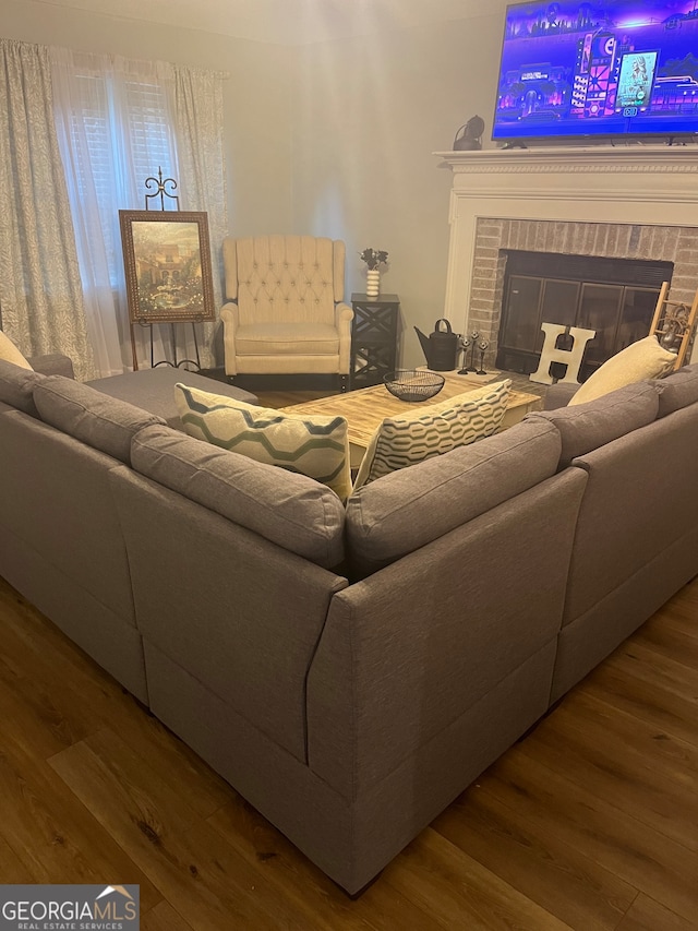 living room featuring a brick fireplace and wood-type flooring