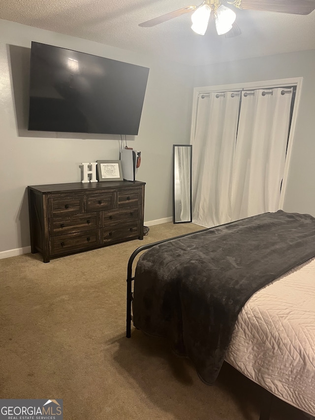 carpeted bedroom with ceiling fan and a textured ceiling