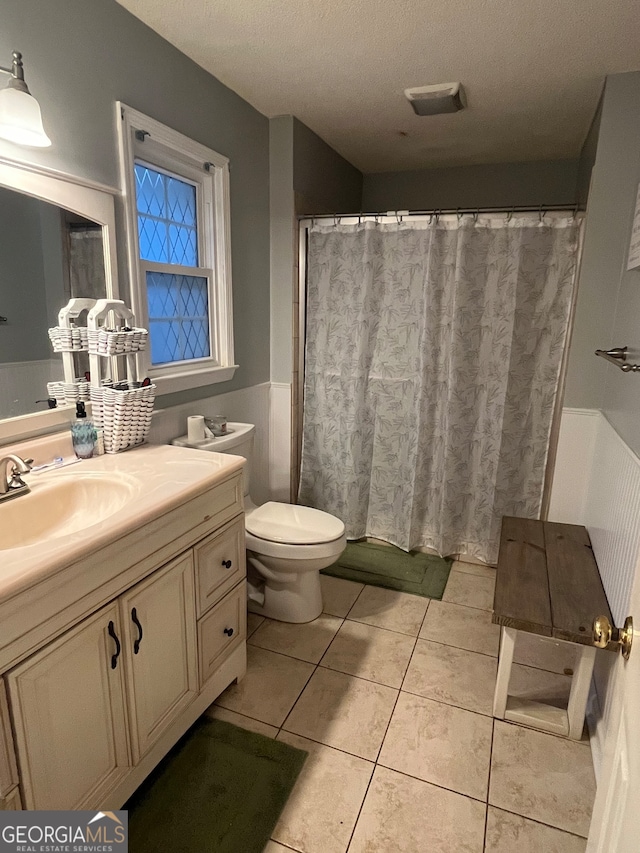 bathroom featuring a textured ceiling, walk in shower, tile patterned floors, vanity, and toilet