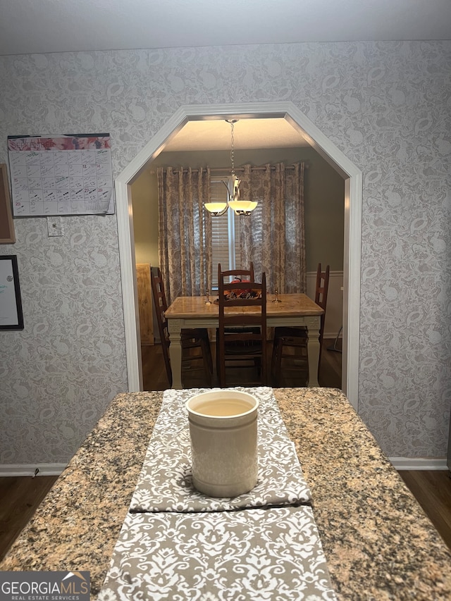 dining space with dark wood-type flooring and a notable chandelier