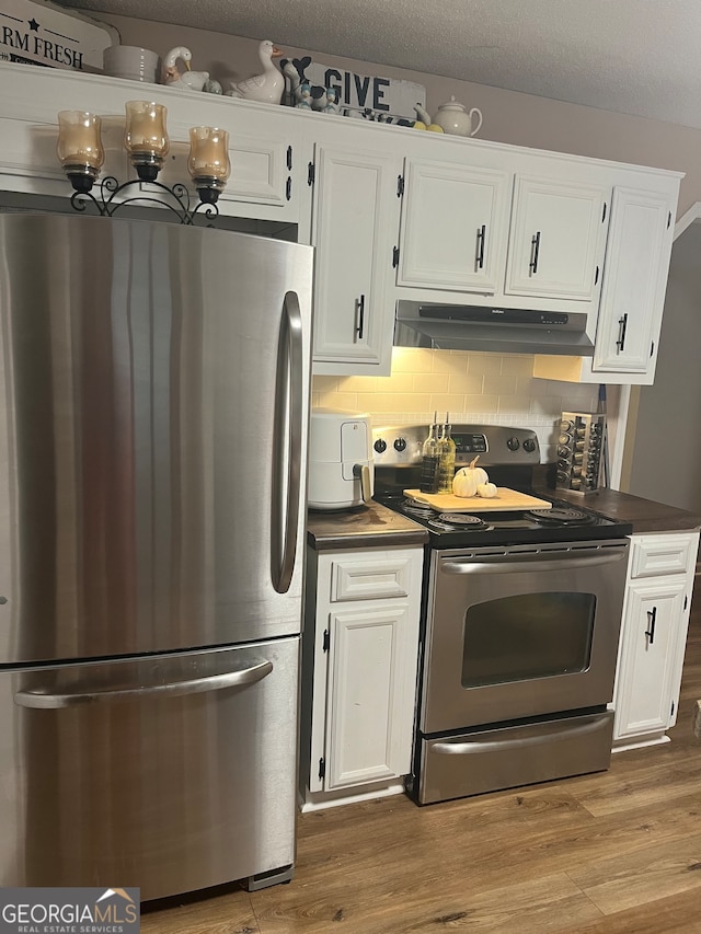 kitchen with white cabinets, backsplash, wood-type flooring, and appliances with stainless steel finishes