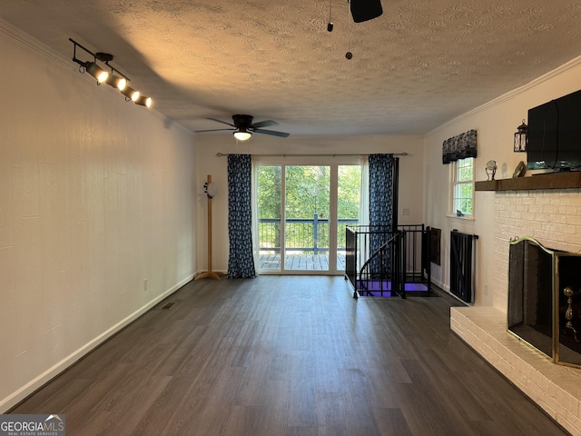 unfurnished living room featuring ceiling fan, a textured ceiling, dark hardwood / wood-style floors, and a brick fireplace