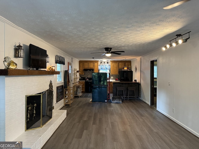 living room featuring ceiling fan, a brick fireplace, crown molding, and a textured ceiling