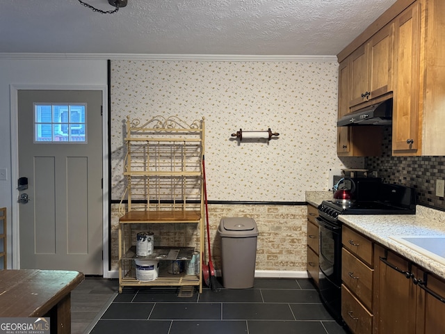 kitchen featuring dark tile patterned floors, a textured ceiling, decorative backsplash, ornamental molding, and gas stove