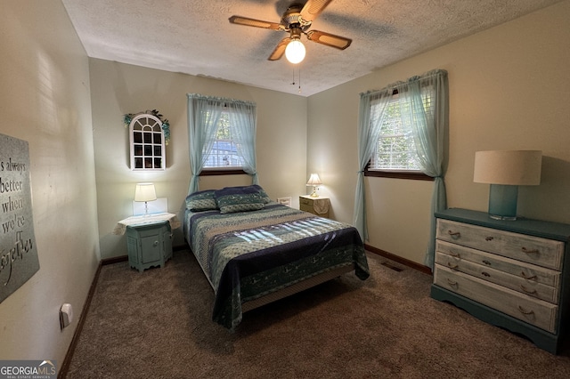 bedroom with a textured ceiling, ceiling fan, dark colored carpet, and multiple windows