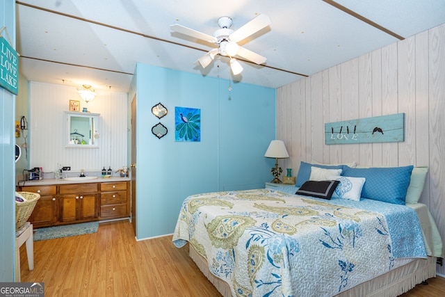 bedroom with ceiling fan, wooden walls, light hardwood / wood-style flooring, and sink