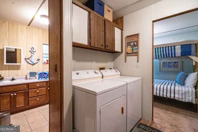 clothes washing area featuring light carpet, a textured ceiling, cabinets, and sink