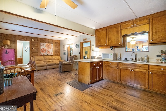 kitchen featuring light wood-type flooring, kitchen peninsula, ceiling fan, and sink