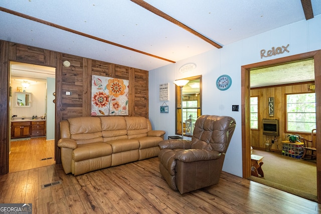 living room featuring wood-type flooring, wood walls, a textured ceiling, and heating unit