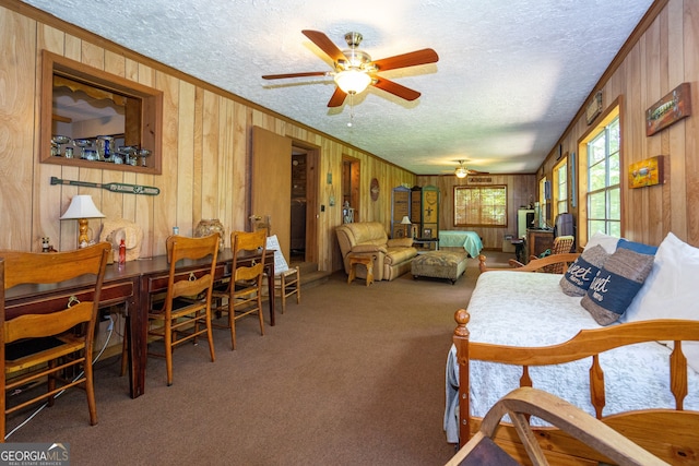 carpeted living room featuring wooden walls, ceiling fan, crown molding, and a textured ceiling