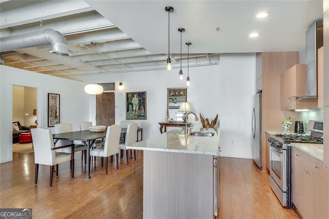 kitchen featuring pendant lighting, light stone counters, sink, stainless steel appliances, and light brown cabinetry