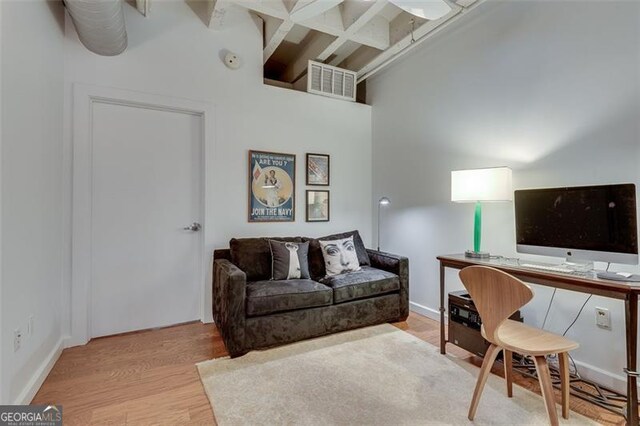 living room featuring a high ceiling, beam ceiling, stacked washer / dryer, and light wood-type flooring