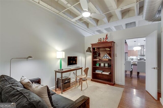 living room featuring light wood-type flooring, a towering ceiling, and beam ceiling