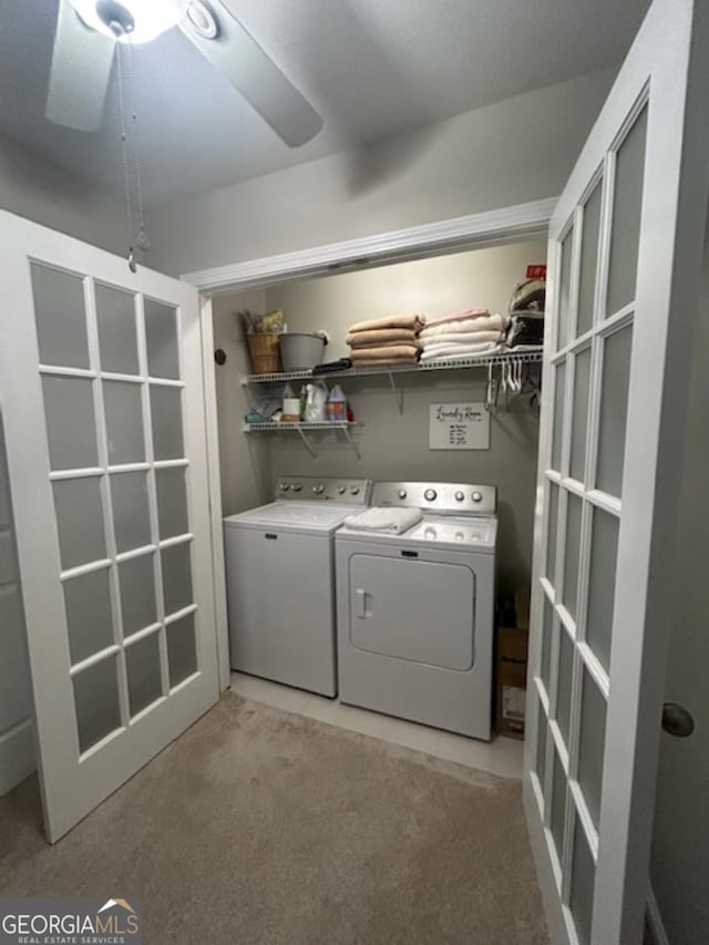 clothes washing area featuring washer and clothes dryer, ceiling fan, and light colored carpet