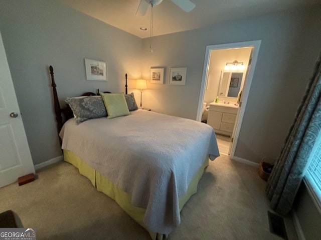 bedroom featuring light colored carpet, ensuite bath, and ceiling fan