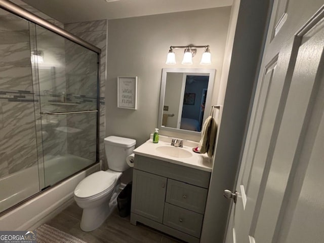 full bathroom featuring wood-type flooring, vanity, toilet, and bath / shower combo with glass door