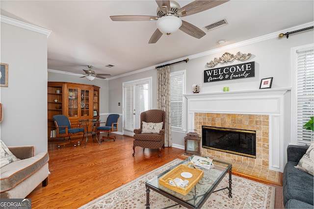 living room with a fireplace, ceiling fan, wood-type flooring, and ornamental molding