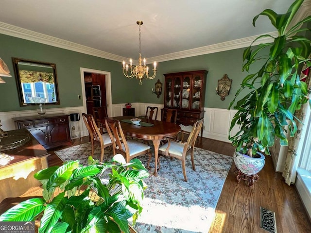 dining area featuring wood-type flooring, ornamental molding, and an inviting chandelier