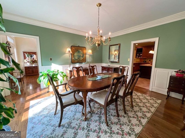 dining space featuring dark hardwood / wood-style flooring, crown molding, and an inviting chandelier