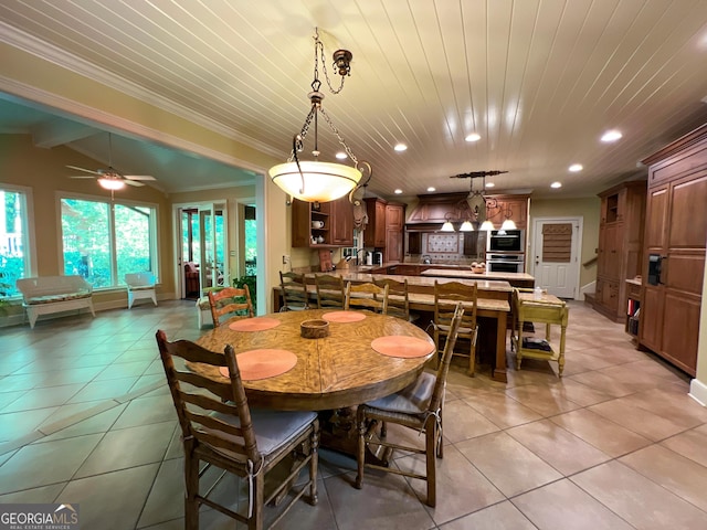 dining area with ceiling fan, lofted ceiling with beams, ornamental molding, and light tile patterned floors