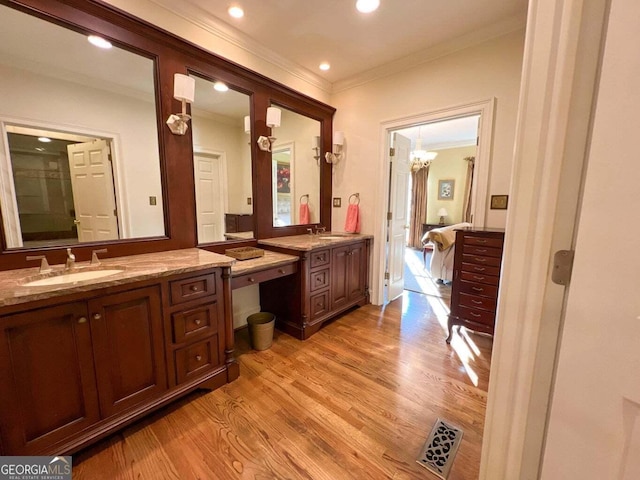 bathroom featuring hardwood / wood-style floors, vanity, ornamental molding, and an inviting chandelier