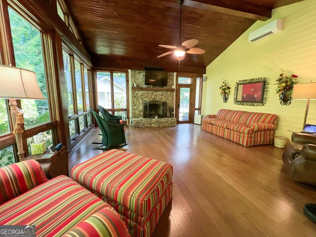 living room with ceiling fan, vaulted ceiling with beams, an AC wall unit, a fireplace, and hardwood / wood-style flooring