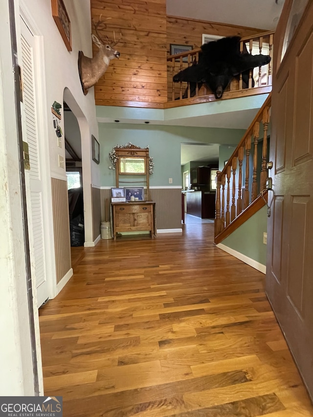 foyer featuring a towering ceiling, hardwood / wood-style floors, and wooden walls