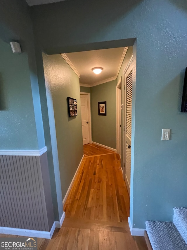 hallway with hardwood / wood-style flooring and crown molding