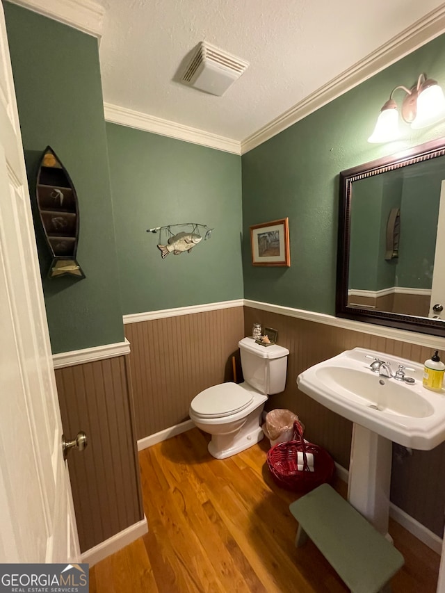 bathroom featuring toilet, hardwood / wood-style flooring, and ornamental molding