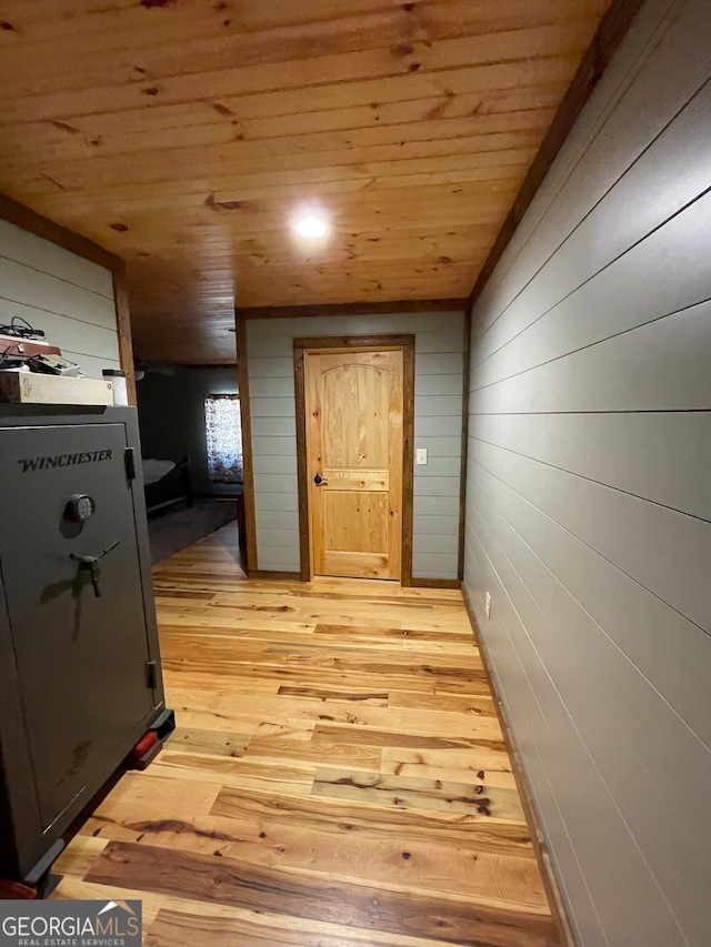 hall featuring wood walls, wood ceiling, and light wood-type flooring