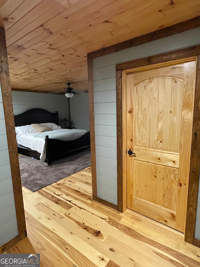 unfurnished bedroom featuring wood ceiling, wooden walls, and light hardwood / wood-style flooring