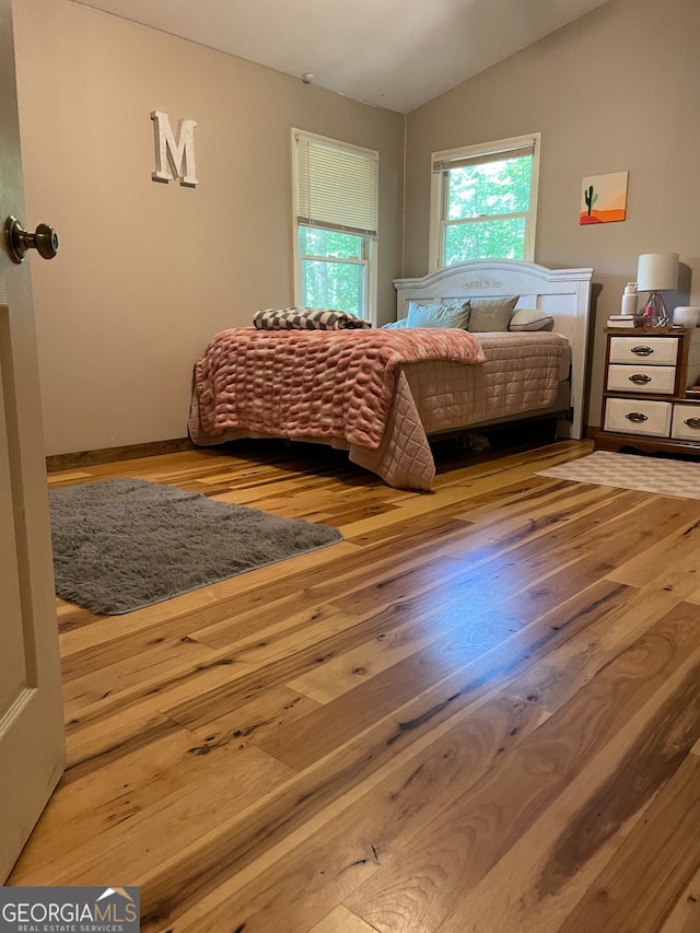 bedroom with hardwood / wood-style flooring and lofted ceiling