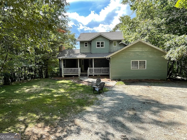 rear view of property featuring covered porch and a yard