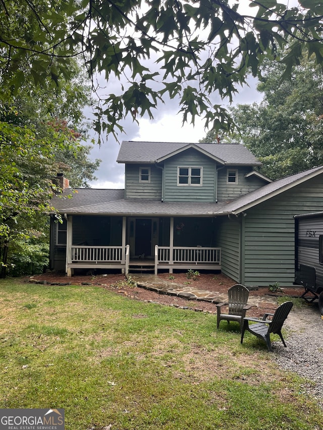 rear view of property featuring a lawn and covered porch