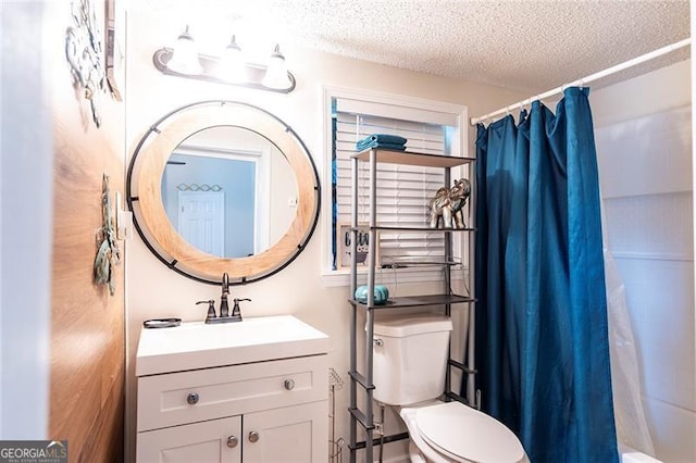 bathroom with vanity, toilet, and a textured ceiling